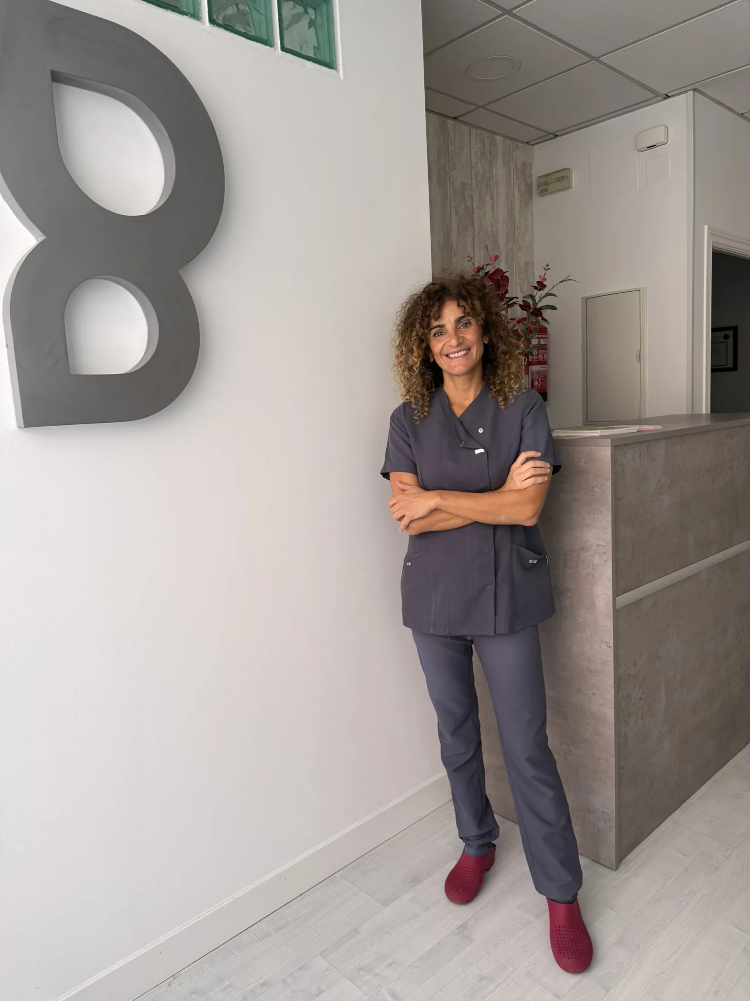 Sala de fisioterapia luminosa con camilla y detalles clínicos en tonos salvia